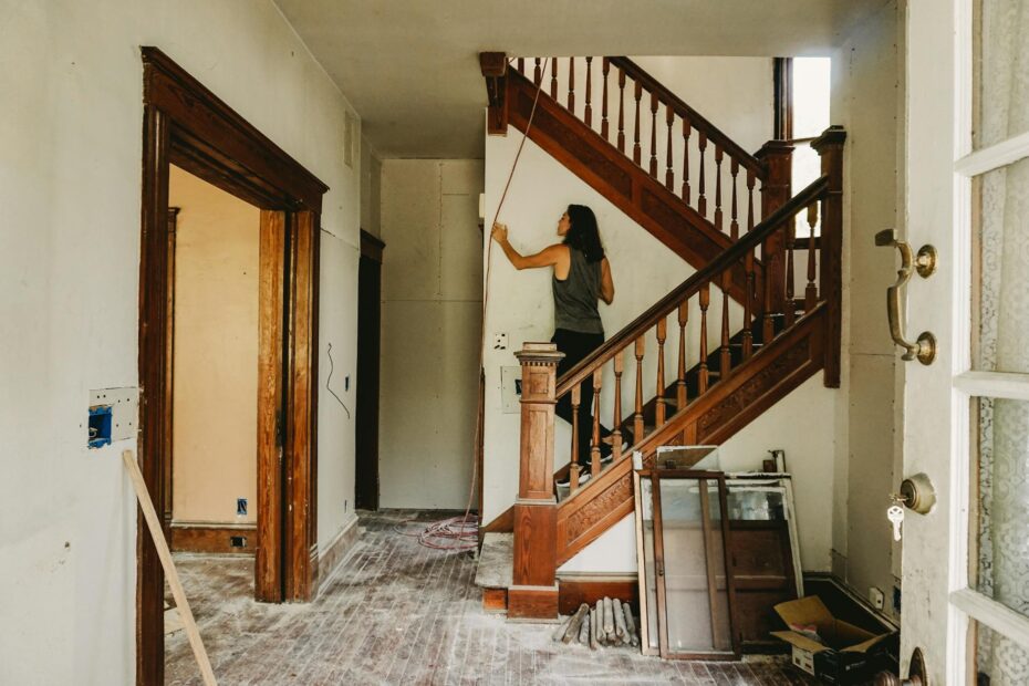 A woman working on home renovation featuring a wooden staircase. (Photo by Monica Silvestre on Pexels)