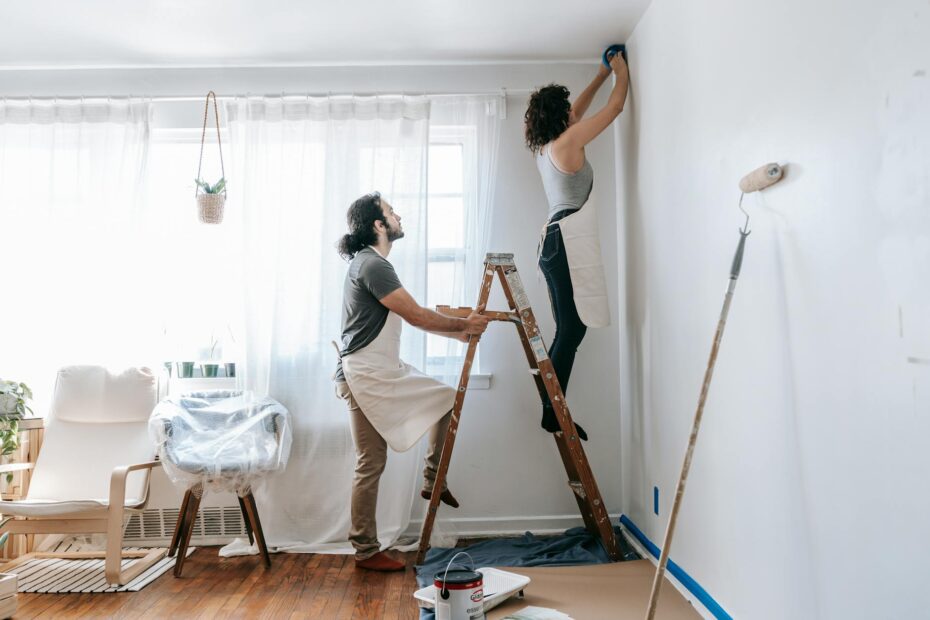 Couple renovating their home, with man supporting ladder and woman working on walls indoors. (Photo by Blue Bird on Pexels)