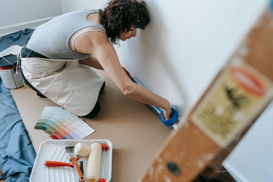 Female using blue tape for home painting project in a modern apartment. (Photo by Blue Bird on Pexels)