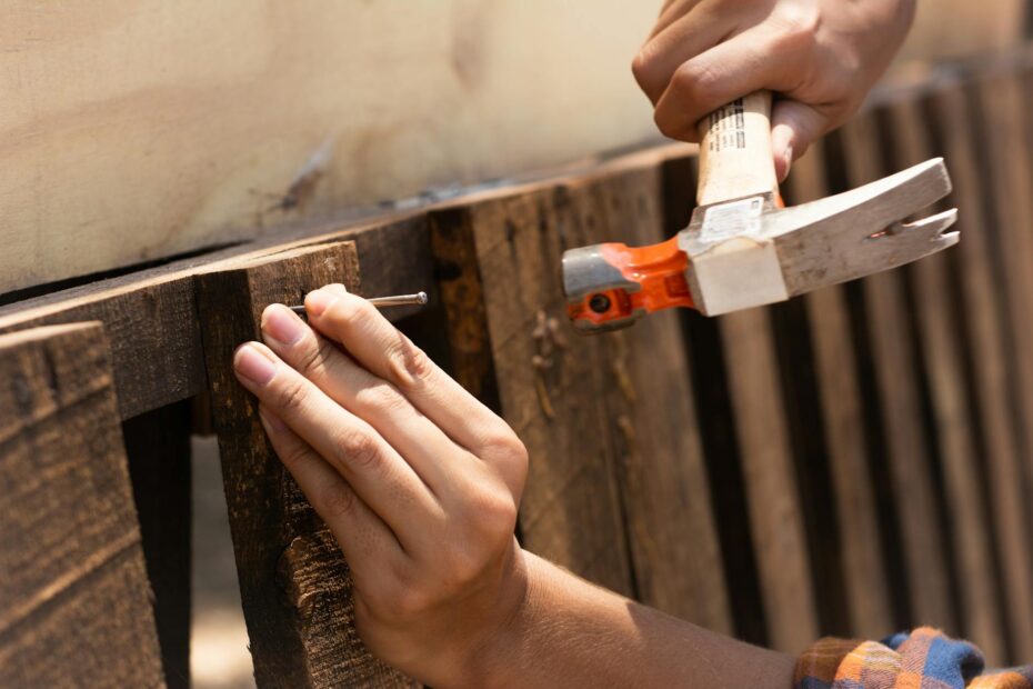 A detailed image showing hands hammering a nail into wooden planks, emphasizing carpentry work. (Photo by Los Muertos Crew on Pexels)