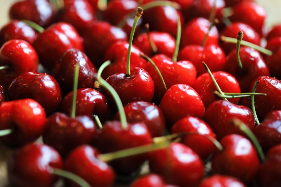A vibrant close-up of fresh red cherries with stems, showcasing their glossy texture and rich color. (Photo by Christina & Peter on Pexels)